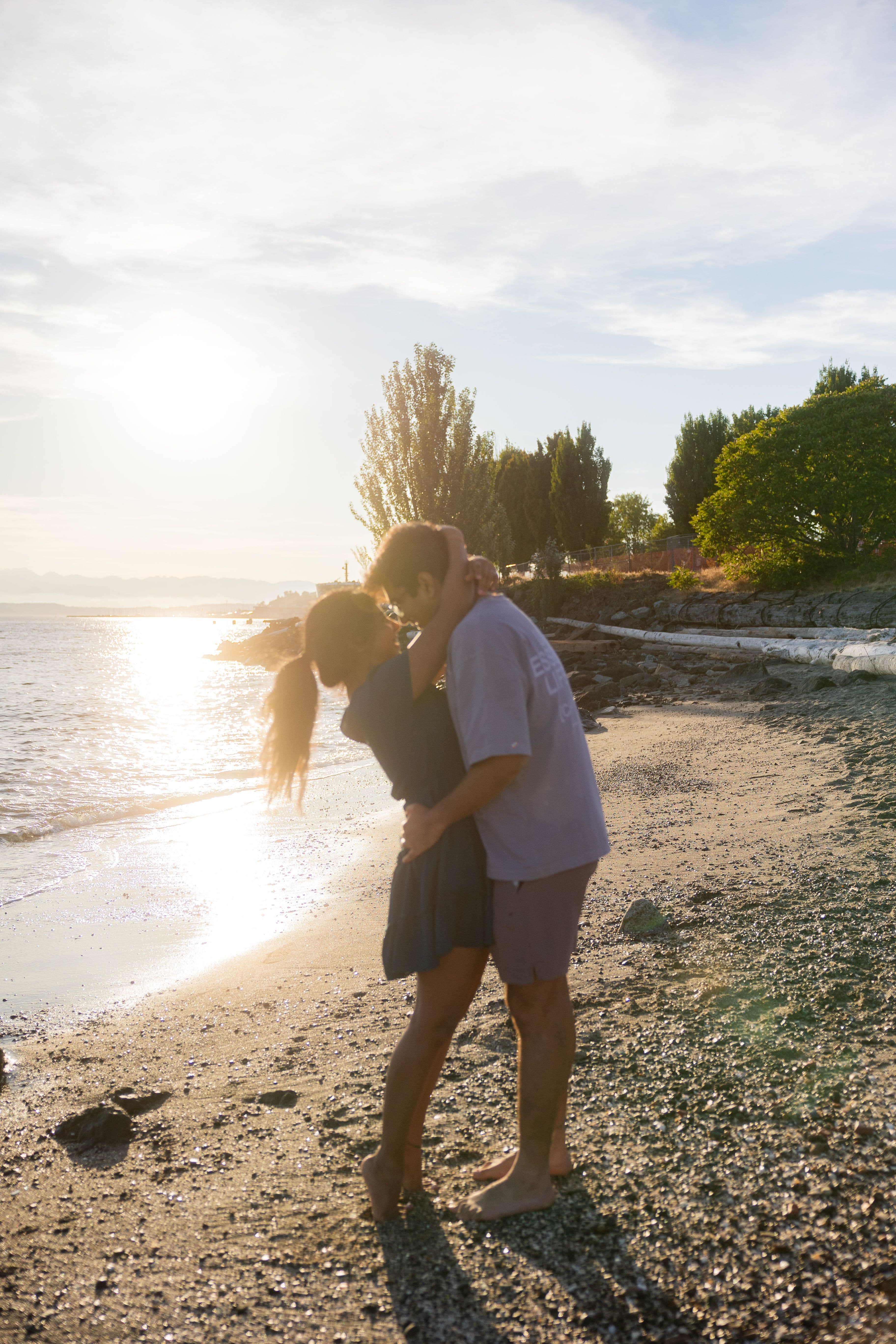 Couple embracing at the beach after a surprise proposal and engagement